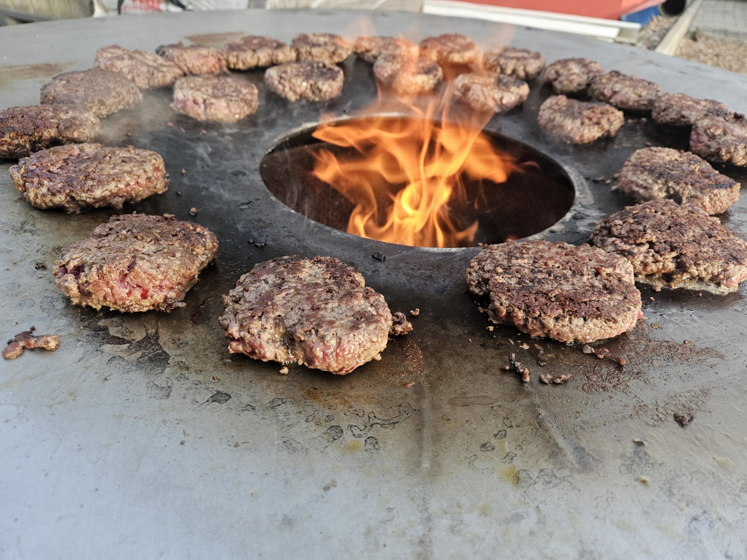 Burgerpattys werden auf einer großen Feuerplatte gegrillt